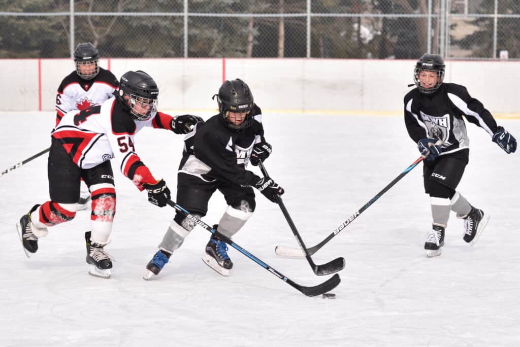 kids playing hockey on an outdoor ice rink
